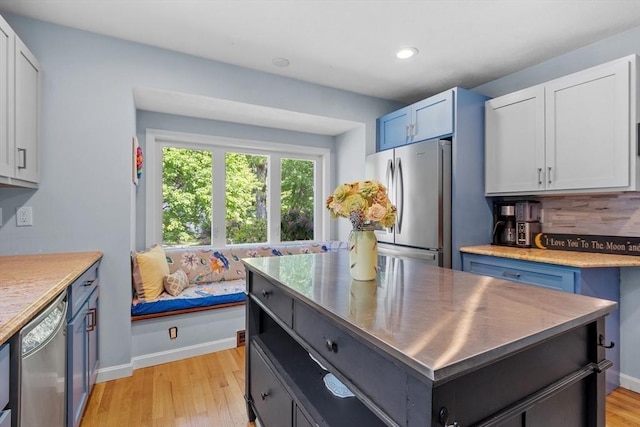 31 Monadnock Dr Unit 31, Westford, MA 01886 - kitchen featuring appliances with stainless steel finishes, light wood-style floors, stainless steel countertops, a kitchen island, and baseboards