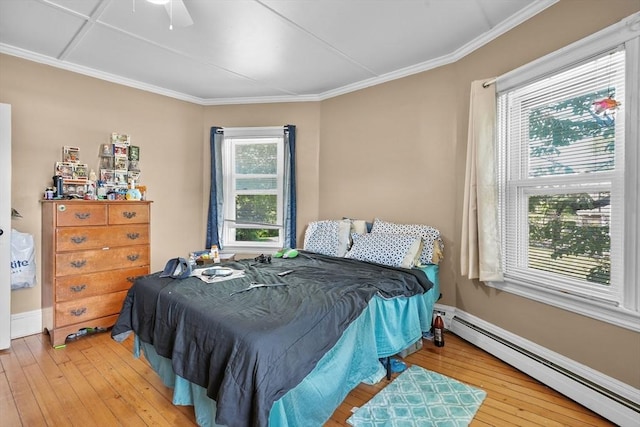 bedroom featuring ornamental molding, light hardwood / wood-style flooring, ceiling fan, and a baseboard heating unit