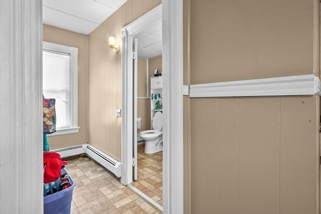 bathroom featuring toilet, baseboard heating, and wooden walls