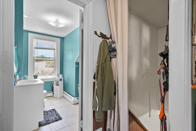 bathroom featuring toilet, tile patterned floors, a baseboard heating unit, and sink