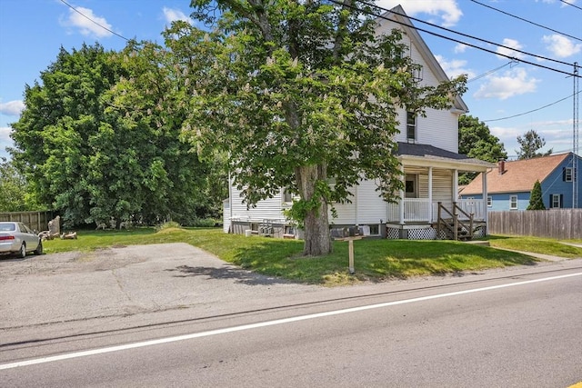 view of property hidden behind natural elements with a front yard and covered porch