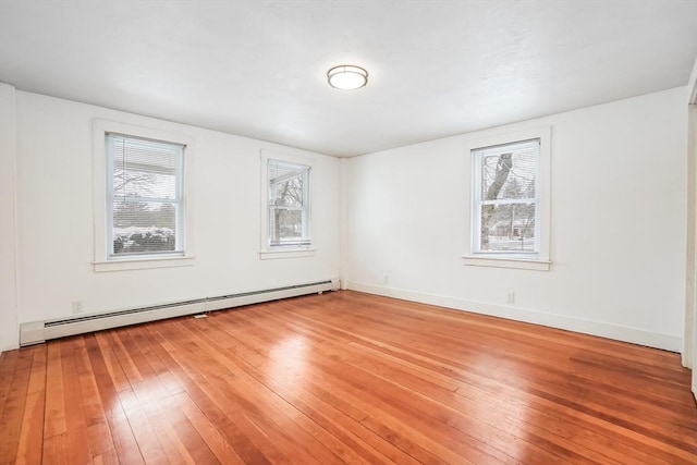 spare room with a baseboard heating unit, light wood-type flooring, and baseboards