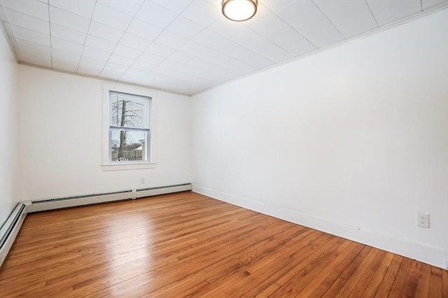 empty room with light wood-style floors, baseboards, a baseboard heating unit, and ornamental molding