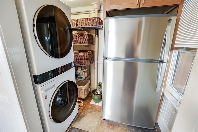 clothes washing area featuring stacked washing maching and dryer and cabinet space