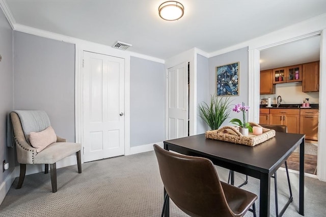 dining room with visible vents, baseboards, carpet, wet bar, and crown molding