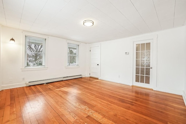 empty room featuring hardwood / wood-style flooring, a baseboard radiator, and baseboards