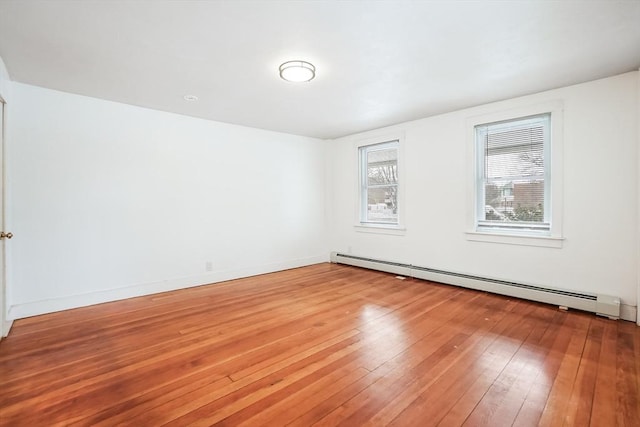 empty room with baseboards, baseboard heating, and hardwood / wood-style floors