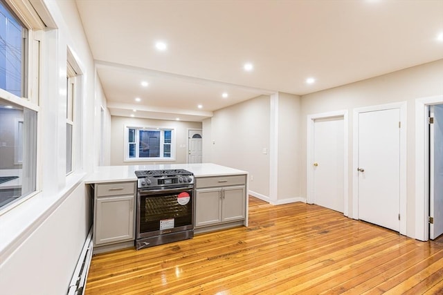 kitchen featuring gray cabinets, light hardwood / wood-style flooring, a baseboard radiator, and stainless steel range with gas stovetop