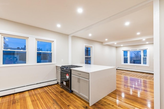 kitchen featuring kitchen peninsula, black gas stove, a baseboard radiator, and light hardwood / wood-style flooring