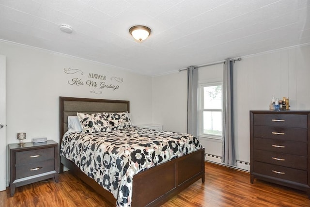 bedroom with a baseboard heating unit, ornamental molding, and dark wood-type flooring