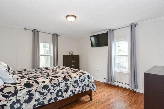bedroom with light wood finished floors and a baseboard heating unit