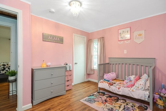 bedroom with crown molding, baseboards, and wood finished floors