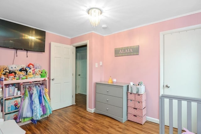 bedroom featuring an inviting chandelier, baseboards, crown molding, and wood finished floors