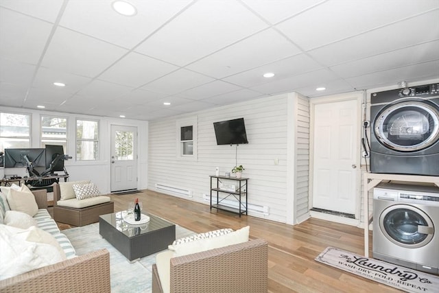 living room with a paneled ceiling, stacked washing maching and dryer, and wood finished floors