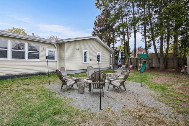view of patio featuring a playground, a fire pit, and fence