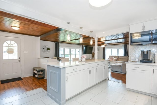 kitchen with a kitchen island, open floor plan, light countertops, stainless steel microwave, and backsplash