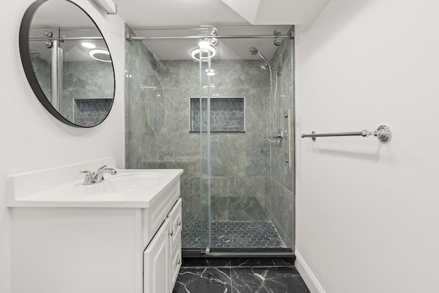 full bathroom with marble finish floors, a stall shower, vanity, and baseboards