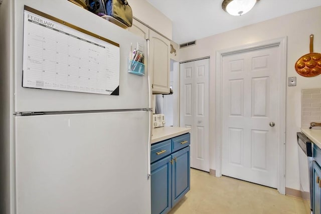 kitchen with blue cabinetry, white fridge, and white cabinets