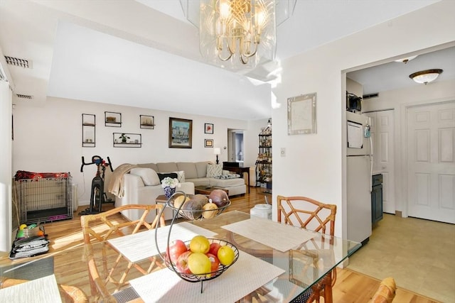 dining area featuring light hardwood / wood-style flooring and a notable chandelier