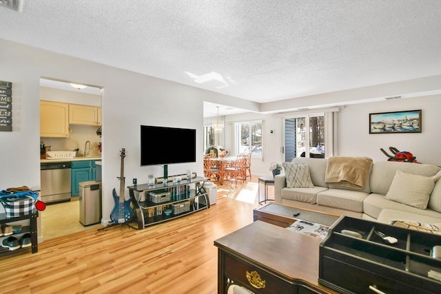 living room with sink, light hardwood / wood-style floors, and a textured ceiling