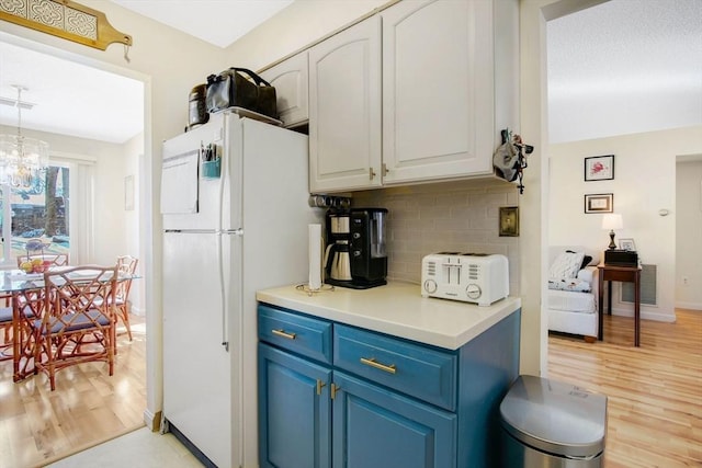 kitchen featuring white cabinetry, backsplash, light hardwood / wood-style floors, blue cabinets, and white fridge