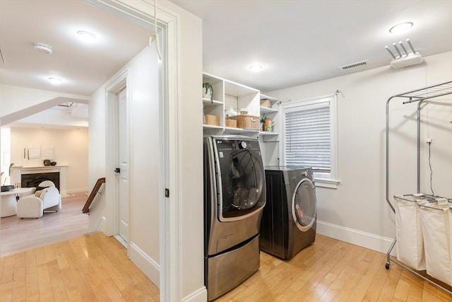 laundry area with washer and clothes dryer and light hardwood / wood-style floors