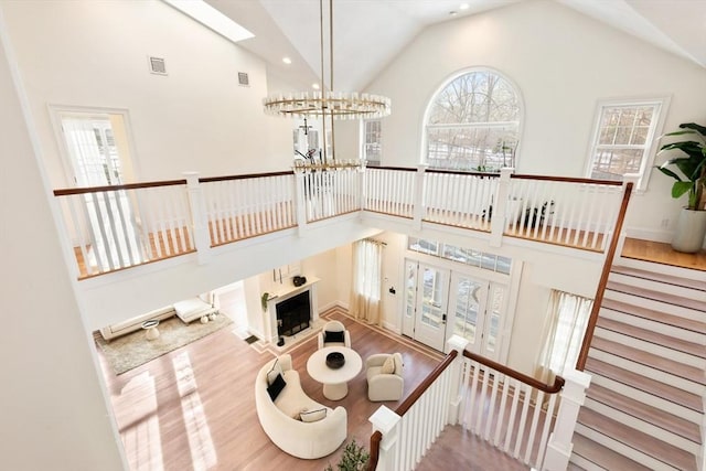 living room featuring a chandelier, high vaulted ceiling, and light hardwood / wood-style flooring