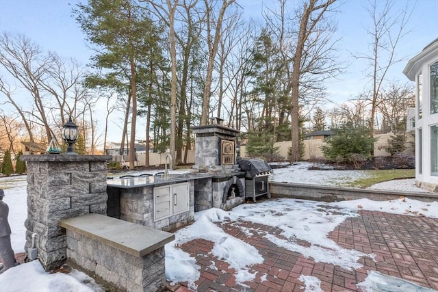 snow covered patio with grilling area, exterior kitchen, and sink