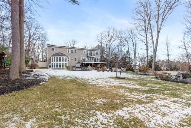 snow covered house featuring a playground, a yard, and a deck