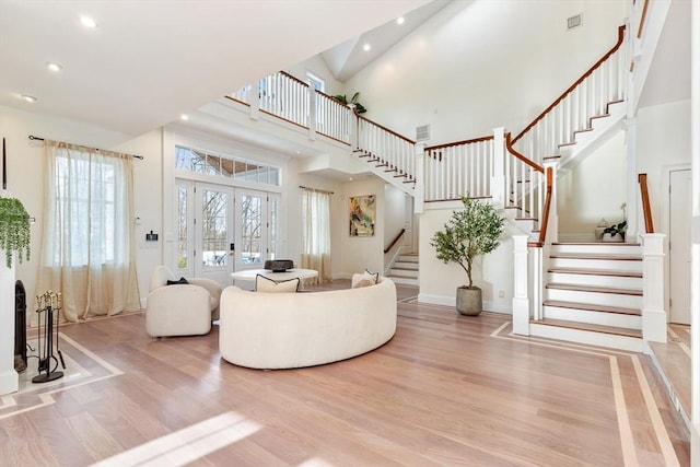 living room with a high ceiling, light hardwood / wood-style floors, and french doors