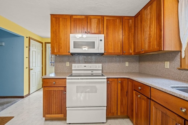 130 Surrey Ln, Brewster, MA 02631 - kitchen with light floors, baseboards, brown cabinets, and white appliances