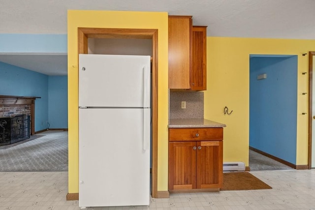 130 Surrey Ln, Brewster, MA 02631 - kitchen with light floors, brown cabinetry, a brick fireplace, and freestanding refrigerator