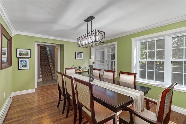 dining space with ornamental molding, an inviting chandelier, dark hardwood / wood-style flooring, and a baseboard heating unit