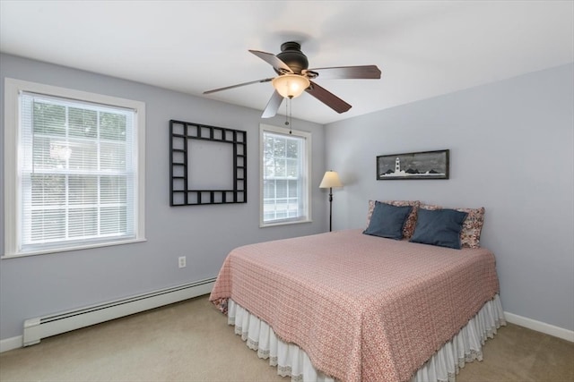 carpeted bedroom featuring ceiling fan, multiple windows, and a baseboard heating unit