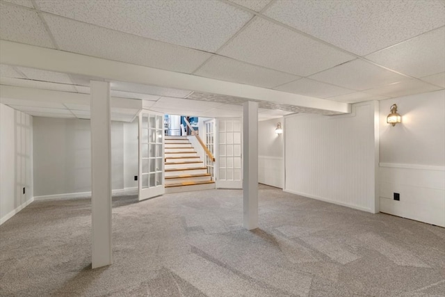 basement featuring a paneled ceiling and carpet flooring