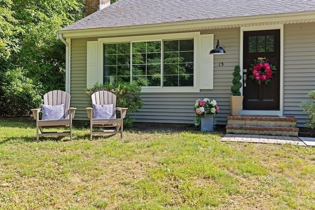 15 Surrey Ln, Sandwich, MA 02563 - property entrance featuring a chimney, a shingled roof, and a yard
