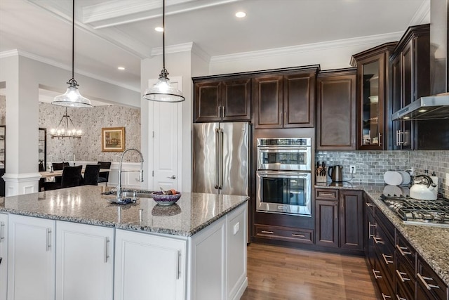 kitchen with stainless steel appliances, wood finished floors, glass insert cabinets, a sink, and light stone countertops