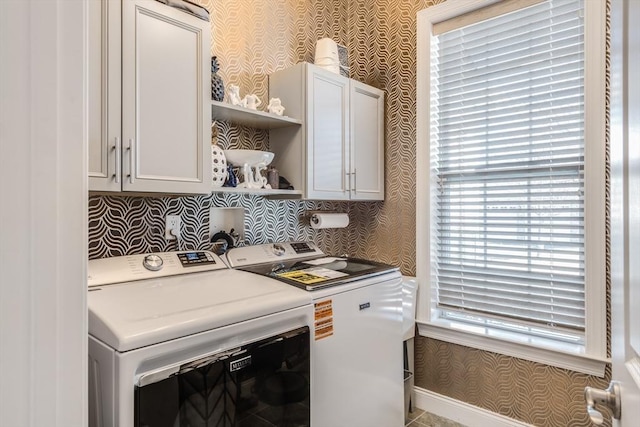 laundry area featuring washing machine and dryer, cabinet space, and wallpapered walls