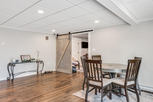 dining area with a barn door, wood finished floors, visible vents, and recessed lighting