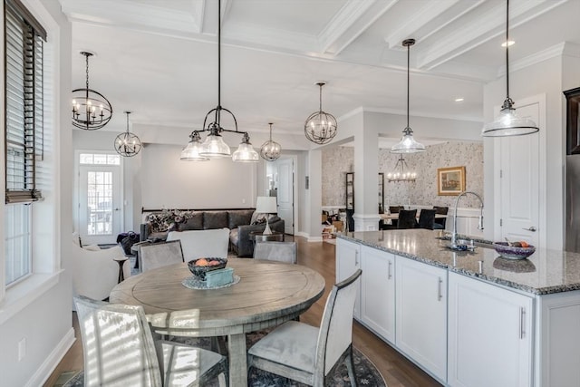 dining room featuring dark wood finished floors, an inviting chandelier, ornamental molding, beamed ceiling, and baseboards