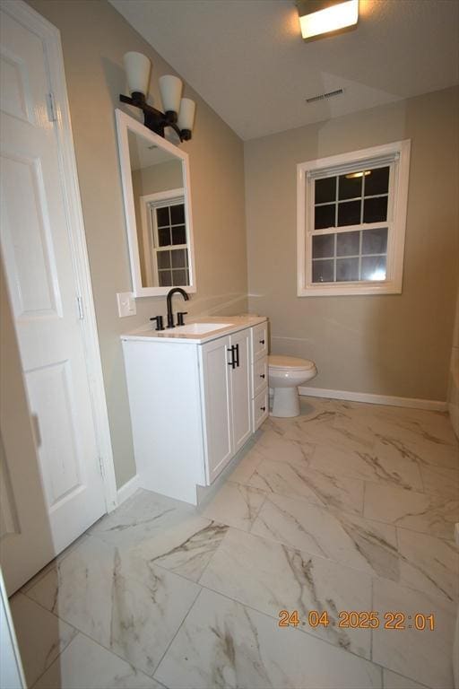 bathroom featuring vanity, toilet, marble finish floor, baseboards, and visible vents