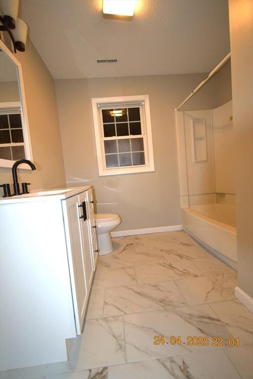 bathroom with vanity, toilet, marble finish floor, baseboards, and shower / washtub combination