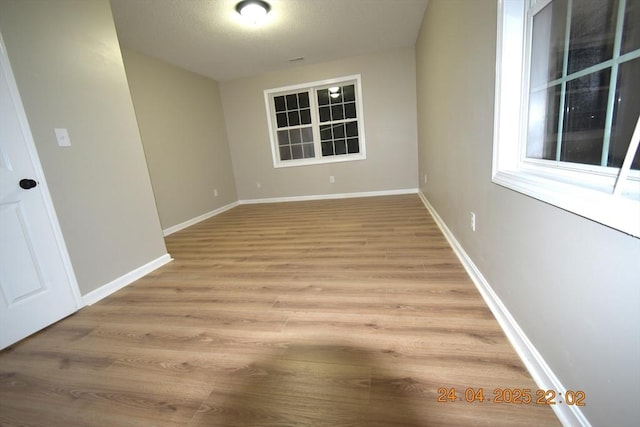 empty room featuring baseboards and light wood-style flooring