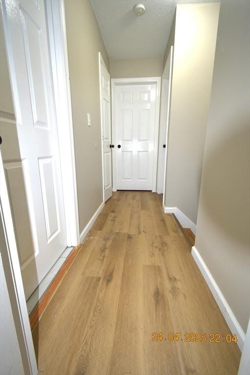 corridor with baseboards and light wood finished floors