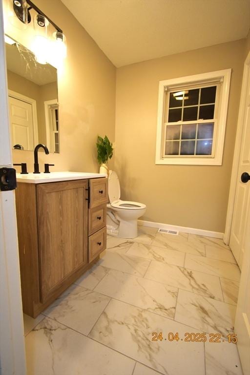 bathroom featuring visible vents, vanity, marble finish floor, toilet, and baseboards