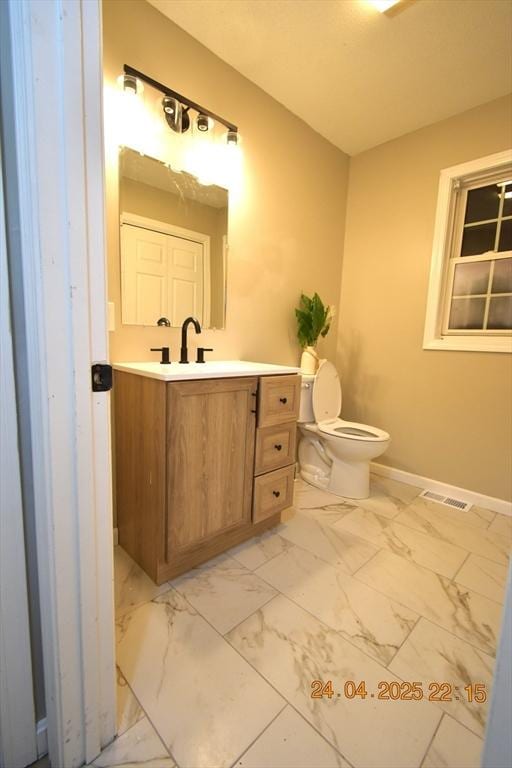 bathroom featuring visible vents, vanity, baseboards, toilet, and marble finish floor