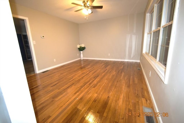 spare room featuring baseboards, ceiling fan, wood finished floors, and visible vents