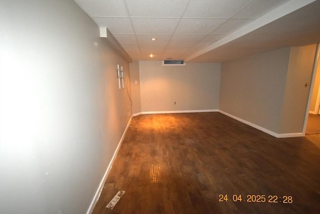 finished below grade area featuring baseboards, recessed lighting, wood finished floors, and a paneled ceiling