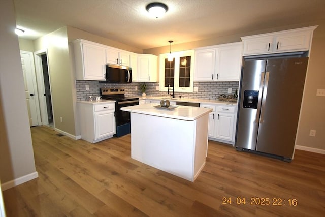 kitchen featuring light countertops, white cabinetry, appliances with stainless steel finishes, and backsplash