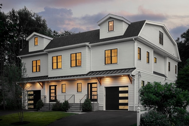 modern farmhouse style home featuring a garage, a lawn, and covered porch